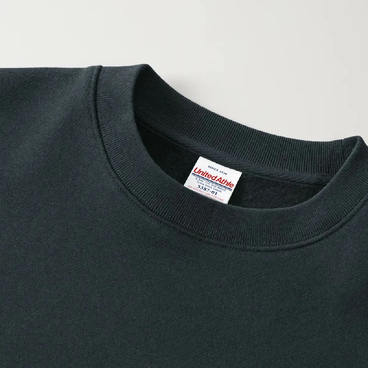 The neck ribbing is finished with double stitching, and the collar tape is made of herringbone tape in the same color as the body, resulting in a durable finish.