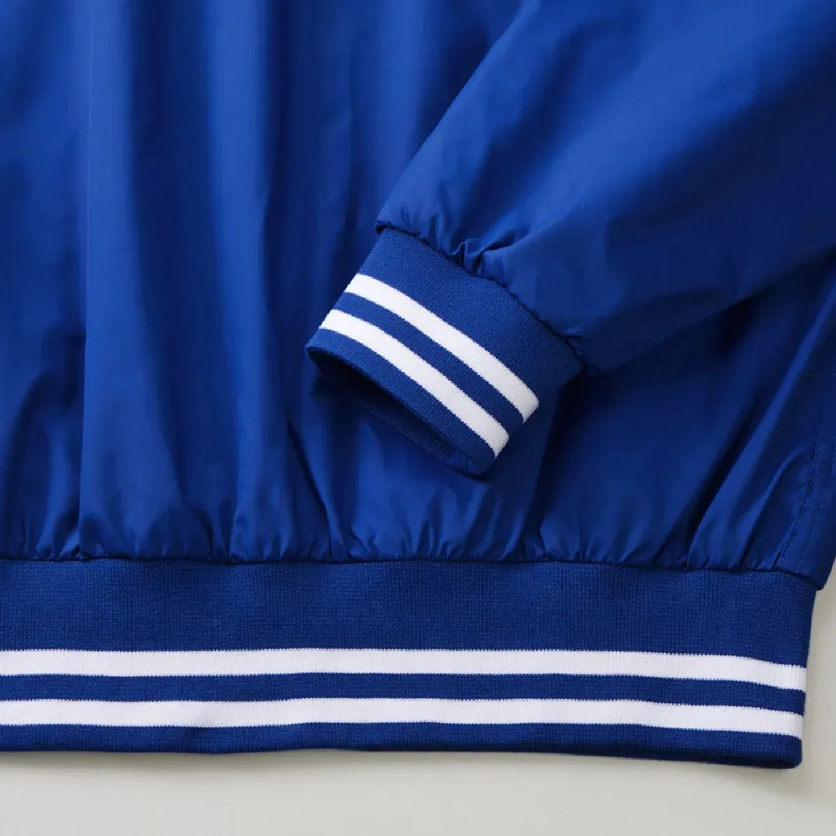 The cuffs and hem feature a fitted ribbed design with contrasting lines.