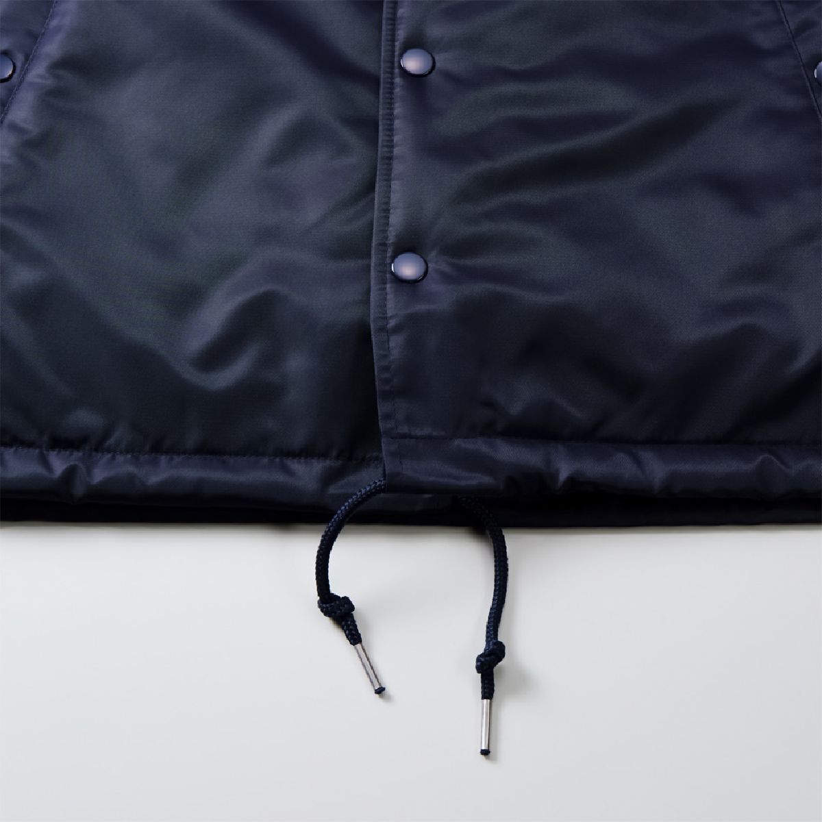 Features a drawstring (round cord) to adjust for wind intrusion and prevent the garment from flapping.
